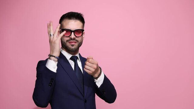 attractive businessman pulling an invisible rope, looking at his capture then kissing his fingers and spreading his kisses all over the place on pink background