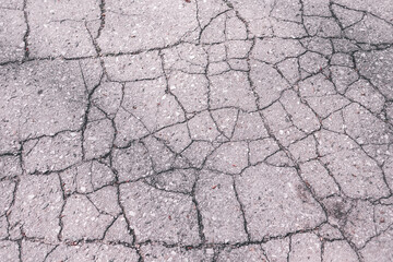 cracked asphalt surface close-up. gray old asphalt test. background ragged road top view