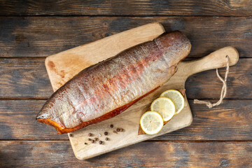 Smoked fish trout. Whole Smoked trout on the serving Board. Smoked trout lay on the wooden kitchen table. Smoked fish close up