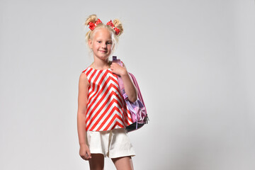 Girl child 7 years old with a school backpack in bright clothes, studio photography