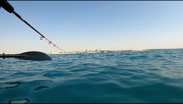 Underwater view of a oblade fish hooked to a lure being pulled out of water by a fisherman standing on a kayak off the coast of Mil Palmeras Beach.