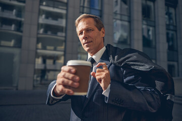 Handsome man with takeaway drink standing on the street