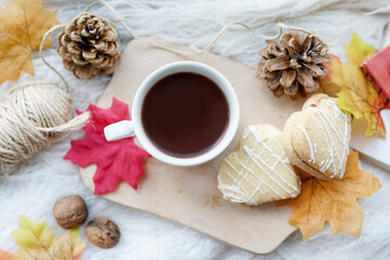 Fototapeta na wymiar Cup of coffee, autumn leaves, cones, cookies on the white table. Autumn concept.