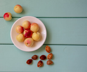Naklejka na ściany i meble Juicy nectarines on a white plate on a light green wooden background