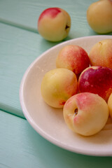 Juicy nectarines on a white plate on a light green wooden background