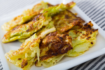 Delicious turnovers of cabbage in batter served on white plate..