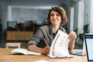 Image of smiling woman writing down notes while sitting at table