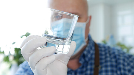 Bartender Wearing a Face Mask and Gloves in His Hands Washes and Cleans an Empty Glass