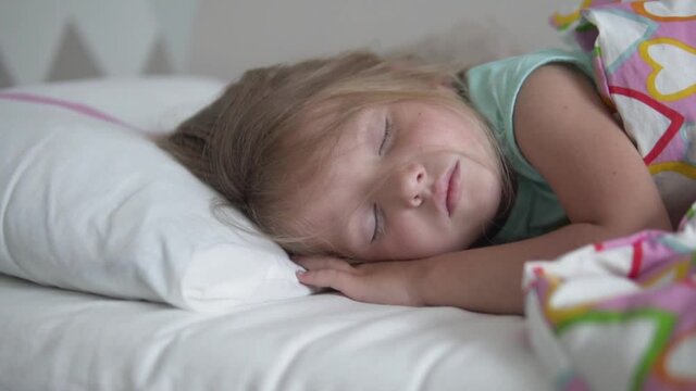 A beautiful little girl sleeps sweetly in her bed.