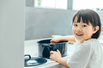 きれいなキッチンで女の子が振り向いて料理をしている　girl kitchen cooking