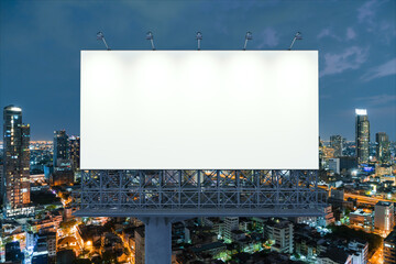 Blank white road billboard with Bangkok cityscape background at night time. Street advertising poster, mock up, 3D rendering. Front view. The concept of marketing communication to promote idea.