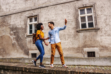 Young beautiful multicultural hipster couple having fun in and old part of the town.