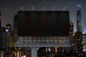 Blank black road billboard with Bangkok cityscape background at night time. Street advertising poster, mock up, 3D rendering. Front view. The concept of marketing communication to sell idea.