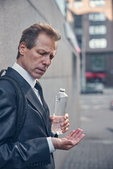 Handsome man in suit holding pill and bottle of water
