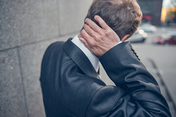 Man in gray jacket touching his neck