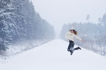 Young woman running in the snow forest