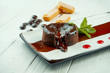 Dessert chocolate fondant. Cupcake with hot black chocolate on a white plate