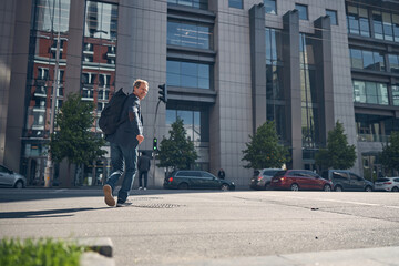 Cheerful man with backpack walking on the street