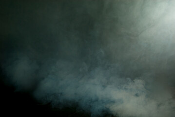 White smoke on a black background. Colored smoke with a blue and green tinge. The texture of scattered smoke. Blank for design. Layout for collages.
