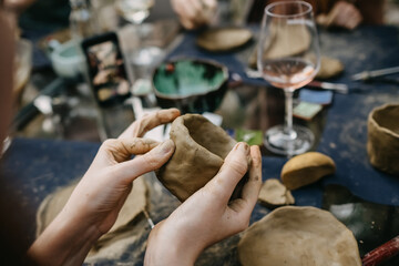 Close up of human hands making a clay bowl. Pottery teaching class.