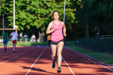 Obraz premium Female runner in sportswear running. Selective focus on the woman and defocused background.