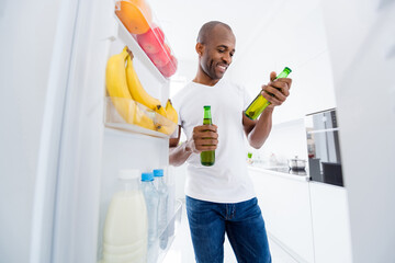 Portrait of his he nice attractive cheerful cheery guy taking from fridge beer bottles spending...