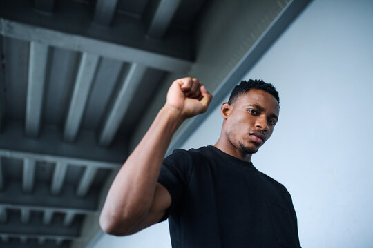 Black man with raised fist standing outdoors in city, black lives matter concept.