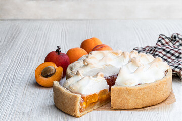 Tasty meringue pie with fresh apricot on wooden table