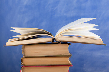 Education and reading concept - group of books on the wooden table, blue blackboard background. Teachers desk