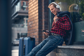 Joyful man using cellphone and listening to music outdoors