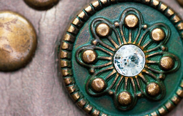 Macro shot of a copper button on a belt, in minimal focus and with a light reflection on the glass bead.  