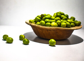 Close up view of green pumps or greengage or olive seeds or belice in a small wooden bowl with white background