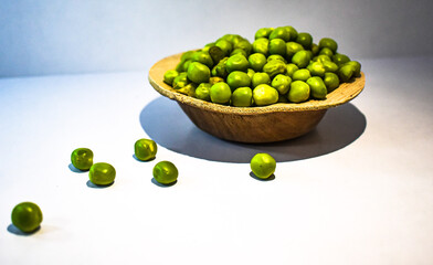 Close up view of green pumps or greengage or olive seeds or belice in a small wooden bowl with white background