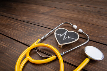 Workplace of a doctor. Stethoscope and little heart on wooden desk background