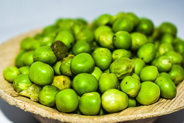 Close up view of green pumps or greengage or olive seeds or belice in a small wooden bowl with white background