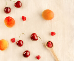 Fototapeta na wymiar cherry, apricot, raspberry ripe berries on a light fabric background