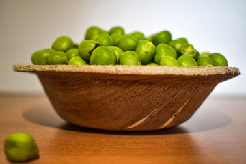 Close up view of green pumps or greengage or olive seeds or belice in a small wooden bowl with white background