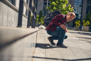 Stylish man suffering from knee pain outdoors