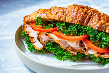 Croissant sandwich with meat, vegetables and green kale, white background. Breakfast food concept.