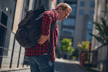 Unhappy man feeling pain in lower back outdoors