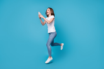 Full length body size view of her she attractive slim fit skinny glad cheerful girl blogger jumping using cell app 5g chatting spend free time isolated bright vivid shine vibrant blue color background