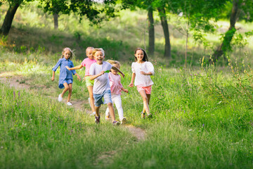 Obraz premium Kids, children running on meadow in summer's sunlight. Look happy, cheerful with sincere bright emotions. Cute caucasian boys and girls. Concept of childhood, happiness, movement, family and summer.