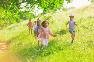 Kids, children running on meadow in summer's sunlight. Look happy, cheerful with sincere bright...