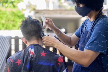 Asian man making haircut and salon business at home. Outdoor barbershop in garden. Social...