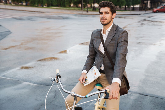 Image of young handsome businessman holding newspaper on bicycle