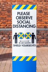 Coronavirus Social Distancing Sign Photographed in a Two Centre Against a Brick Backdrop