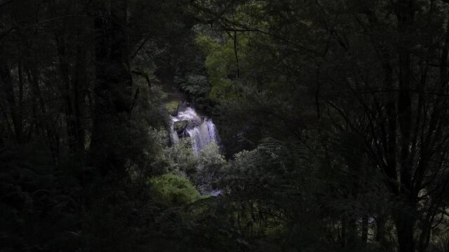 View of large waterfall from afar amongst rainforest greenery