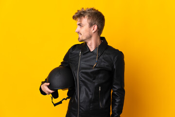 Man with a motorcycle helmet isolated on yellow background looking side