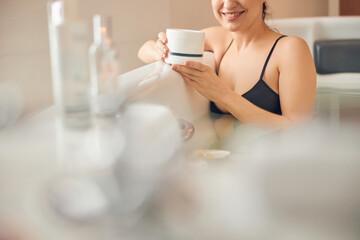 Smiling female with a jar of hair mask
