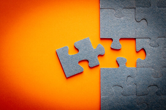 Puzzle. Many puzzle pieces on an orange background. The concept of collective thinking.